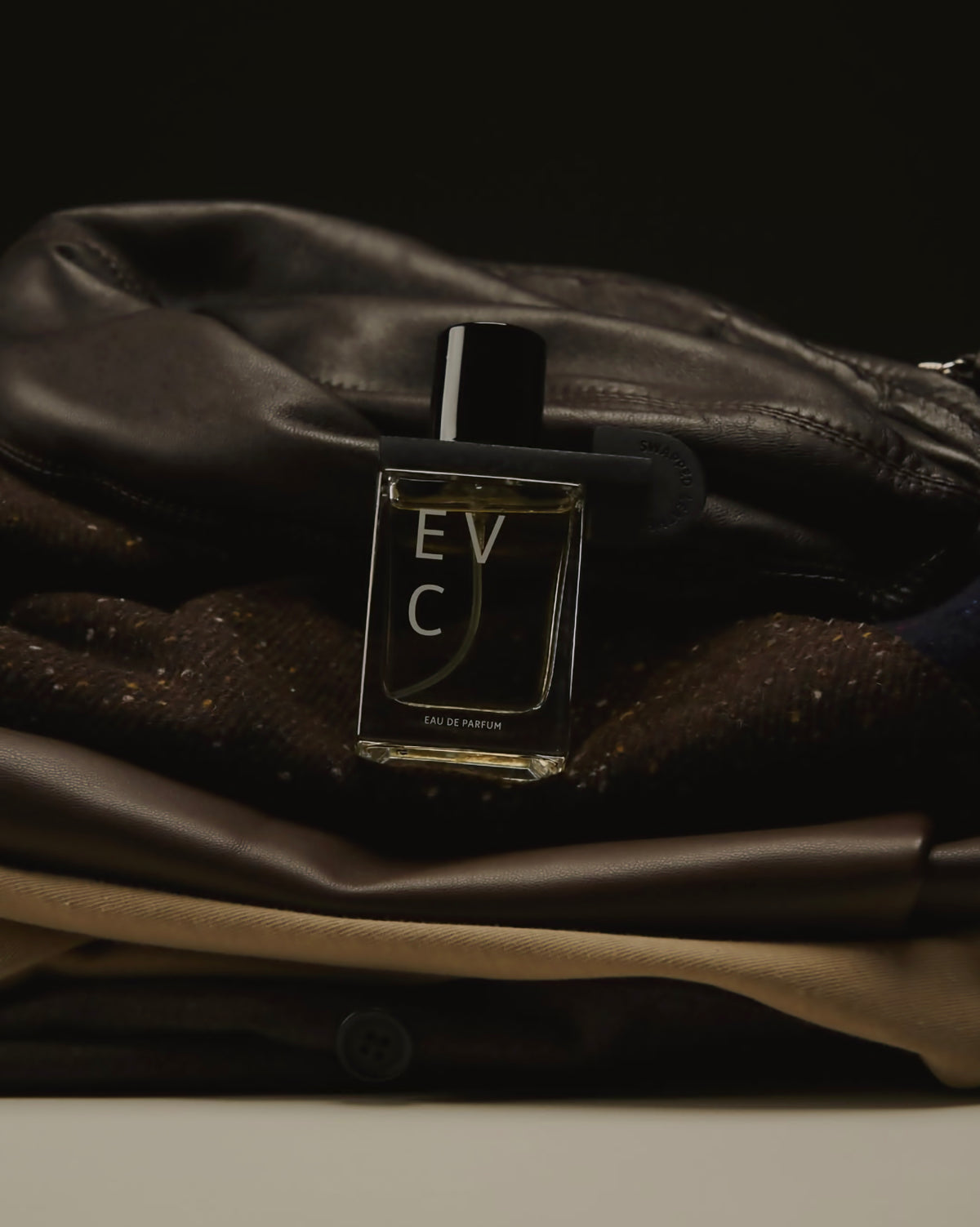 Swapped Leather by EVC resting against a worn leather bag and textured fabric